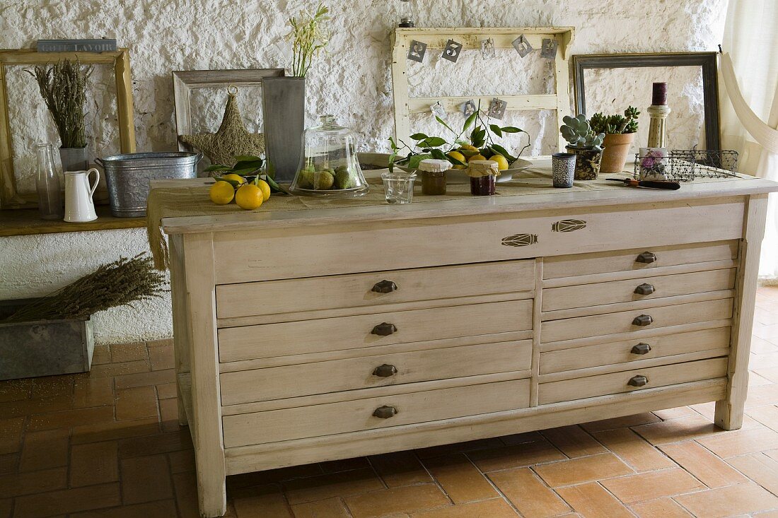 Lemons on old office cabinet painted with cicadas in front of decorative picture frames on roughly plastered wall