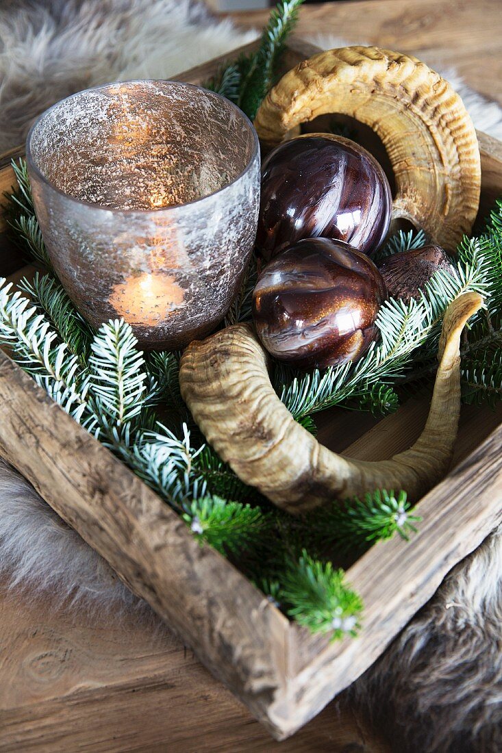 Arrangement of animal horns, baubles and candle lantern on festively decorated tray