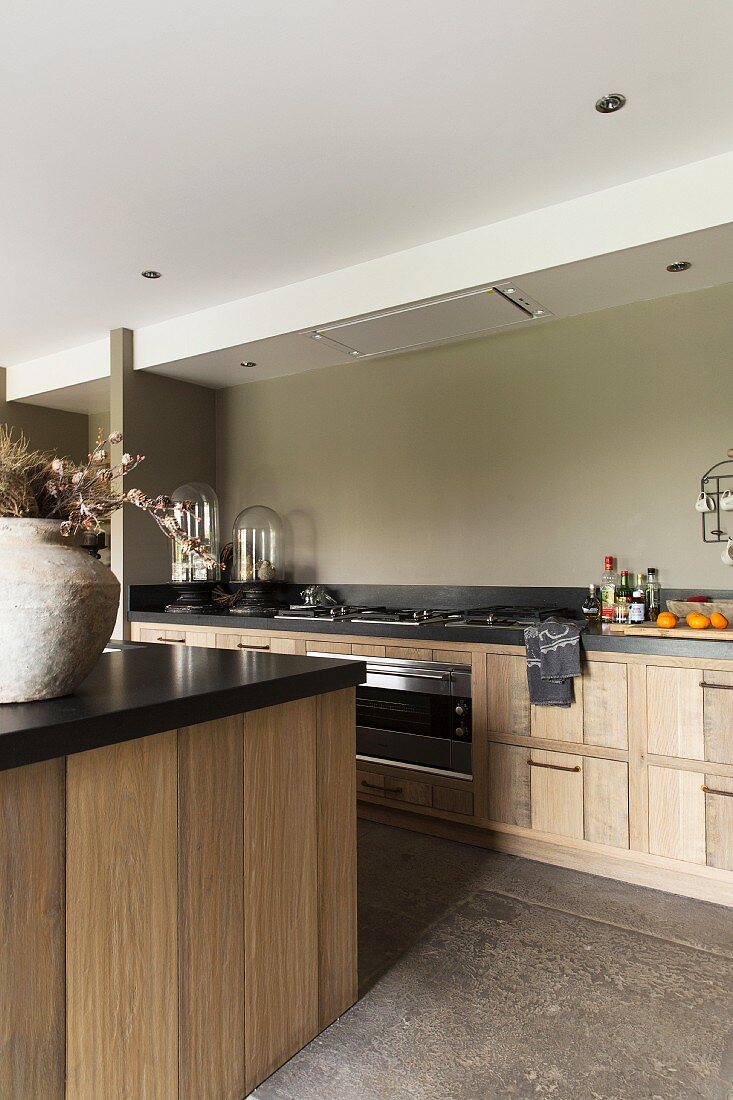 Kücheninsel mit schwarzer Arbeitsplatte gegenüber Küchenzeile in modernem Landhausstil