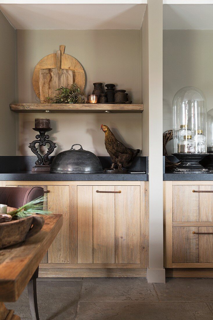 Kitchen counters with dark worksurfaces and wooden fronts separated by partition