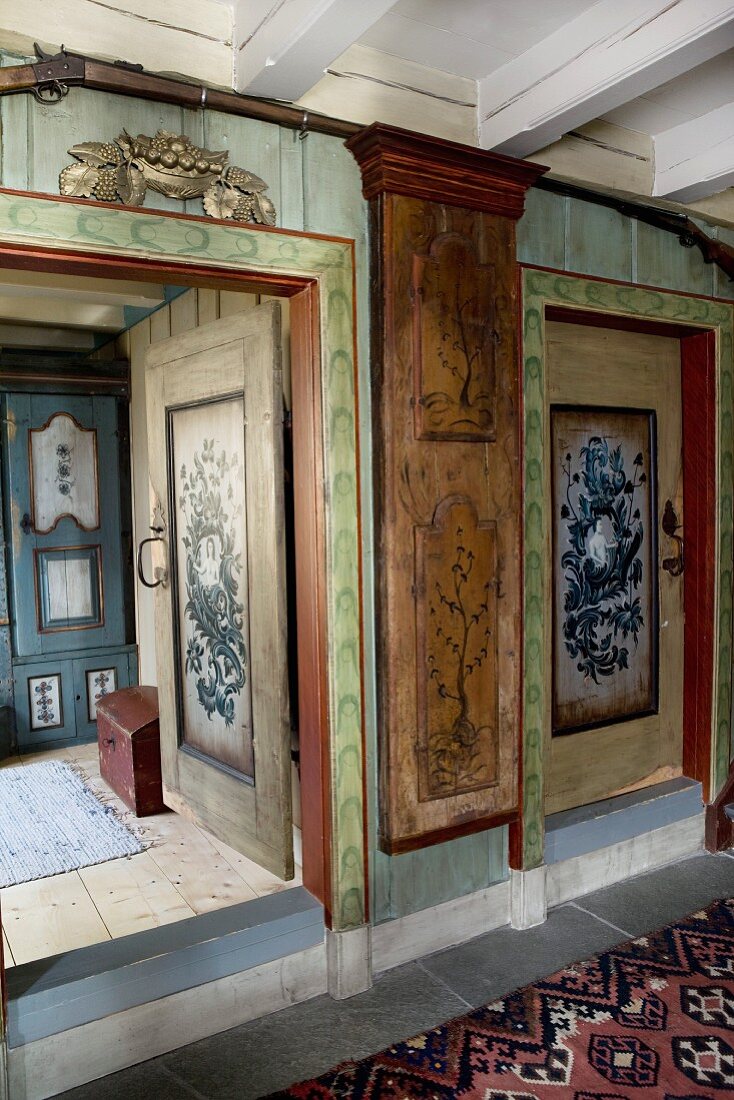 Foyer with painted walls in old wooden house and view of cabinet through open door