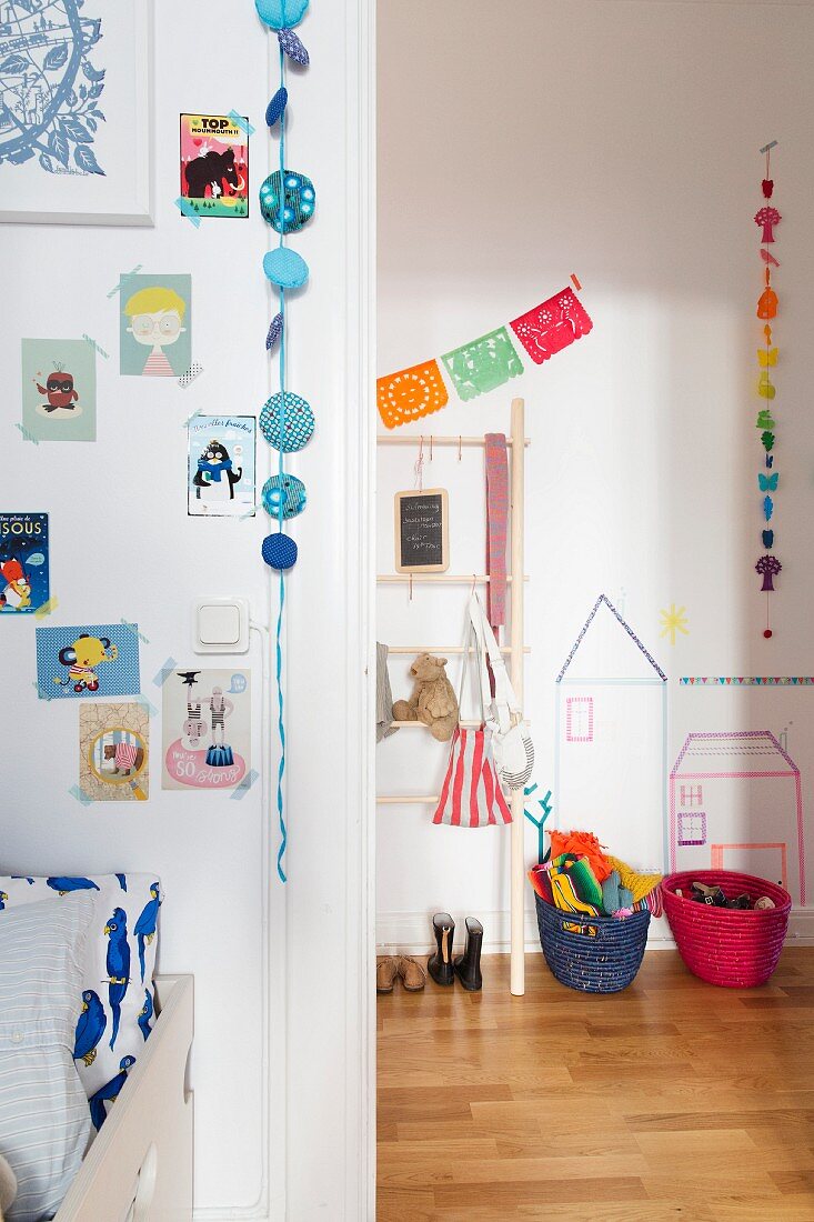 Hand-crafted garlands, comics and pictures stuck to walls with washi tape in child's bedroom; view into cloakroom