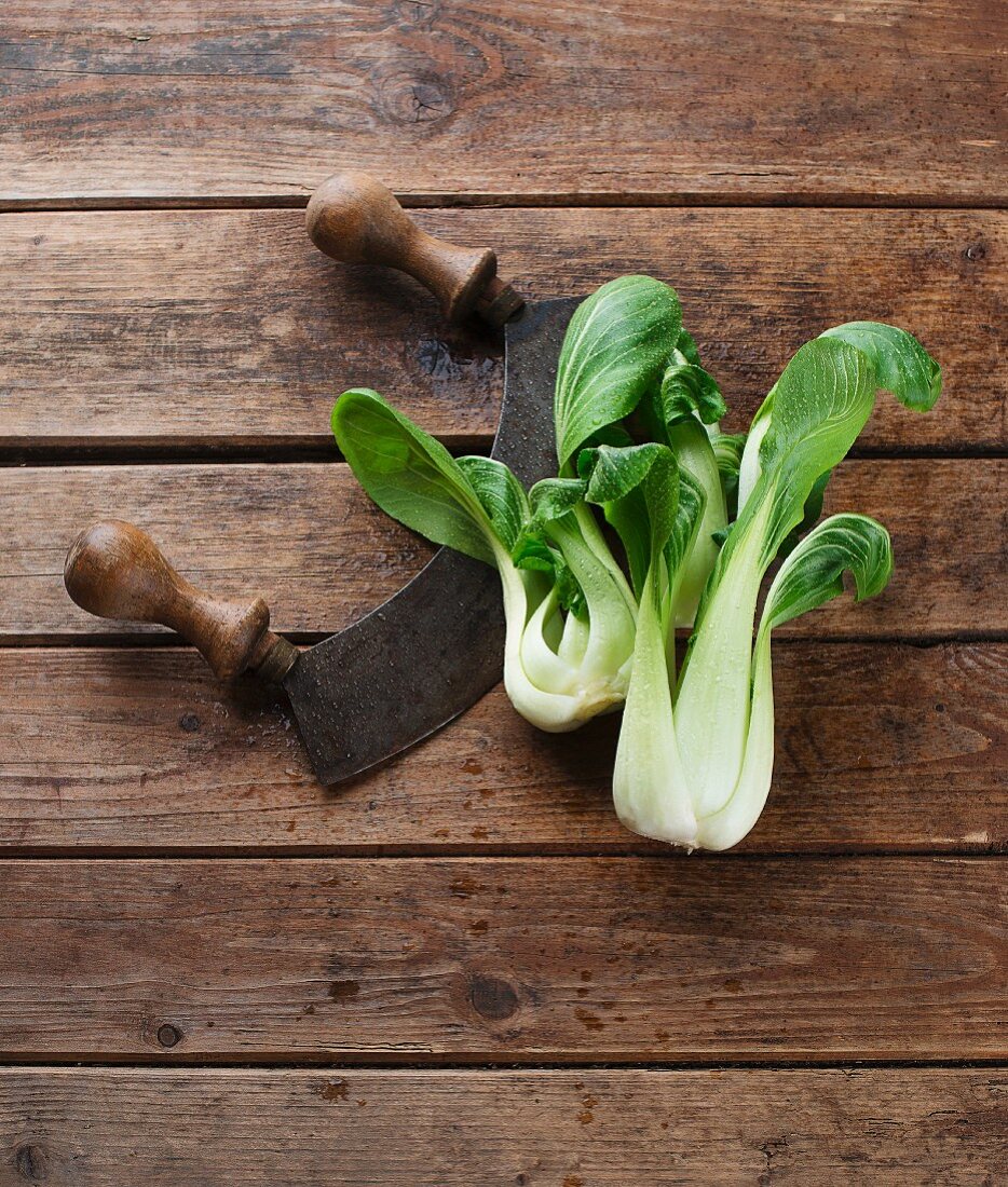 Pak Choi mit Wiegemesser auf Holzuntergrund