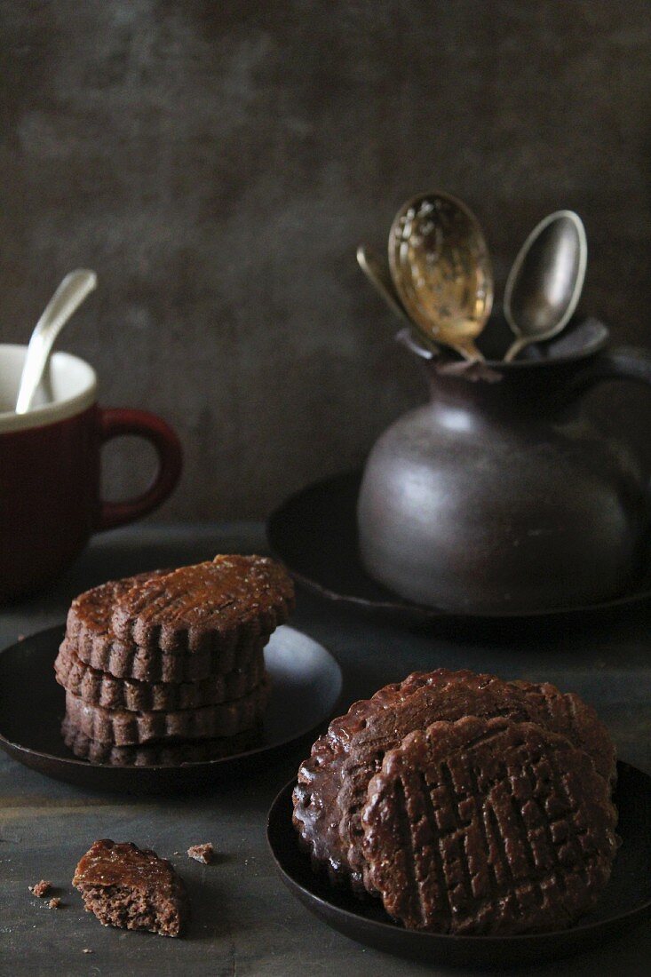 Gestapelte Schokoladenkekse und Krug mit Besteck