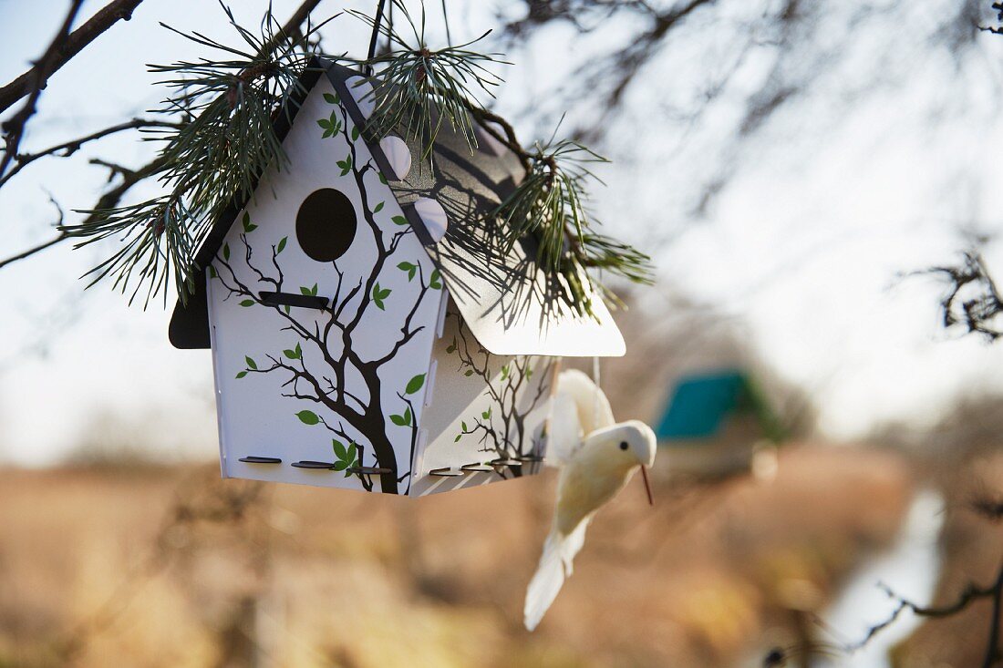 Vogelhäuschen mit Vogelfigur und Kieferzweige Deko