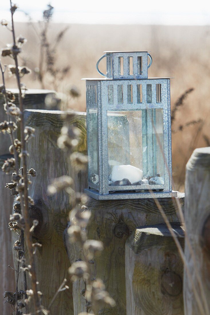 A chrome-plated metal lantern on a wooden stake