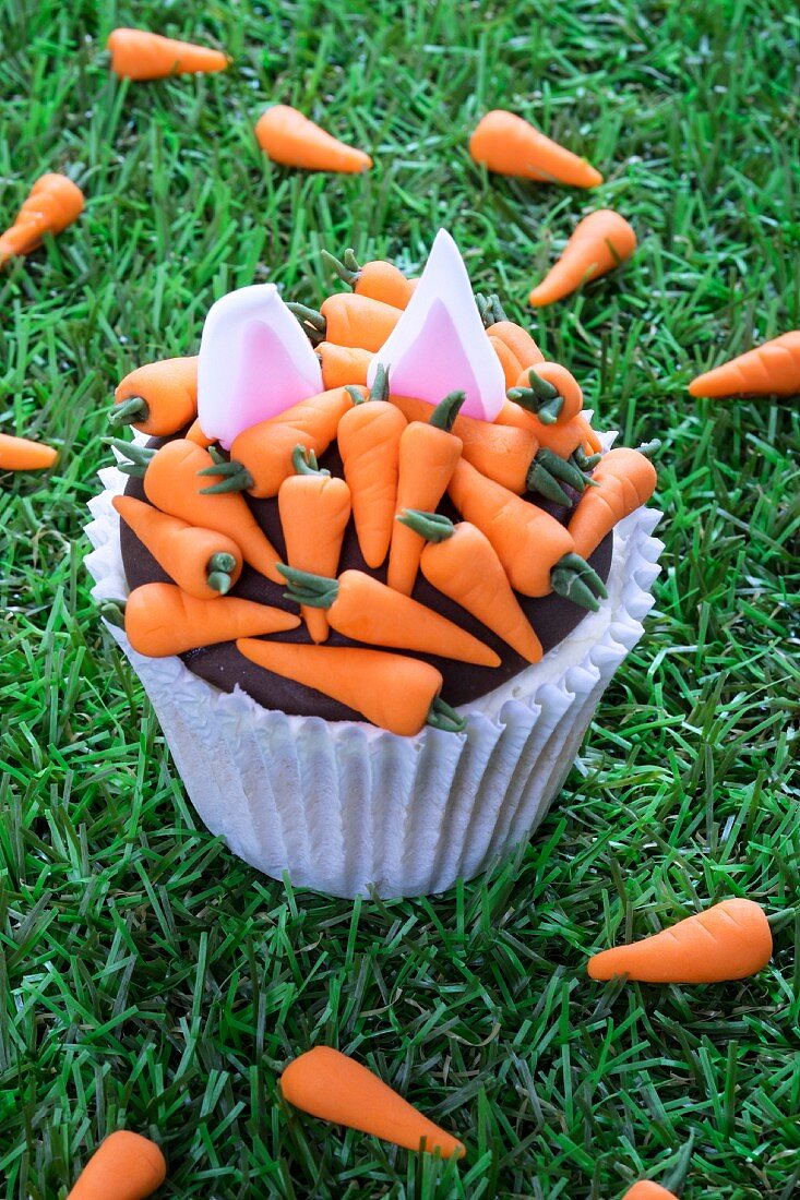 An Easter cupcake decorated with carrots and rabbit ears