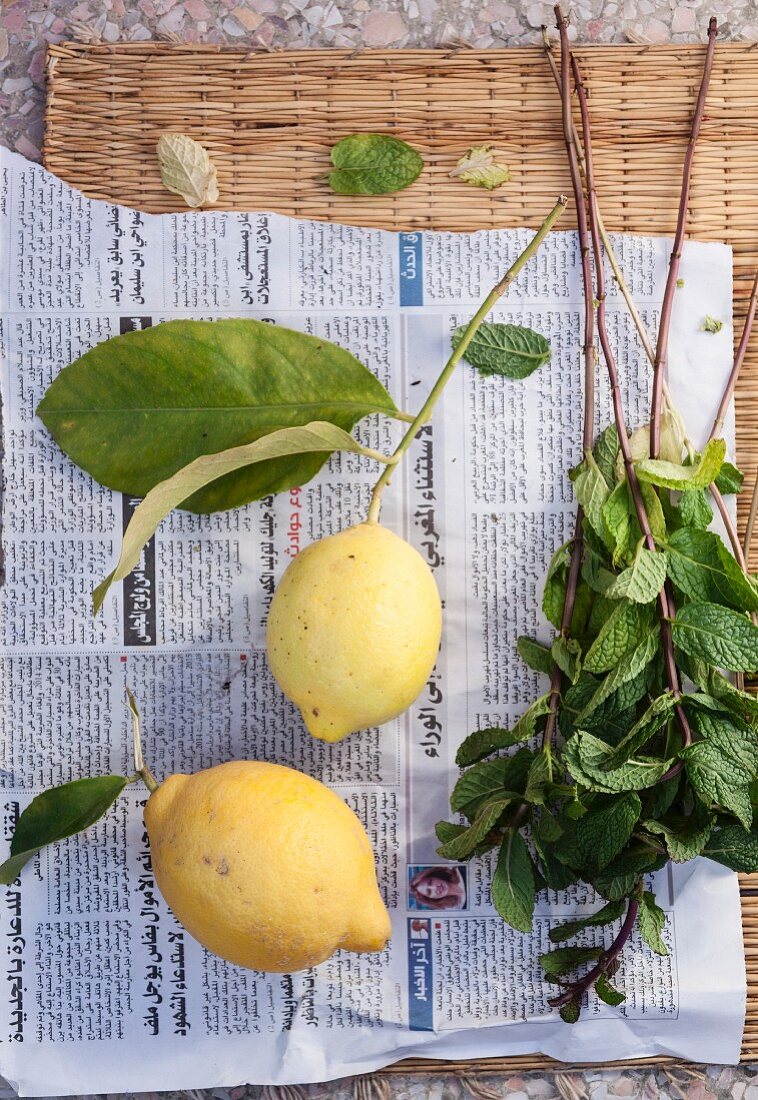 Lemons and fresh mint on a piece of newspaper (seen from above)