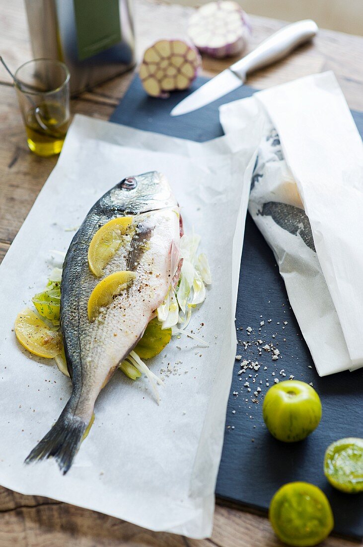 Porgy with green tomatoes and garlic on parchment paper