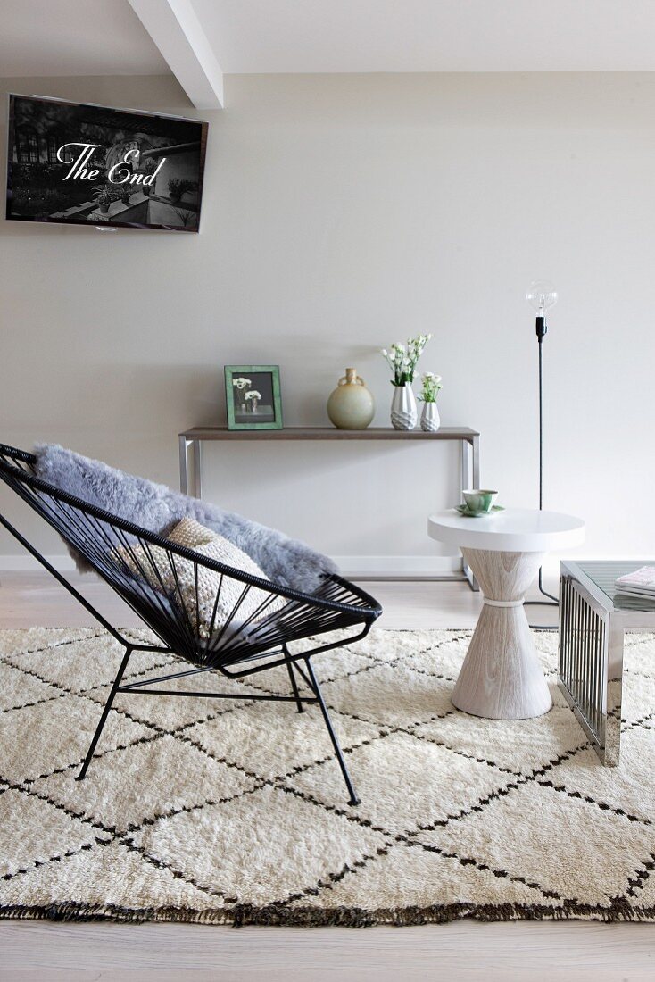 Black, retro cord easy chair and white side table on Berber rug