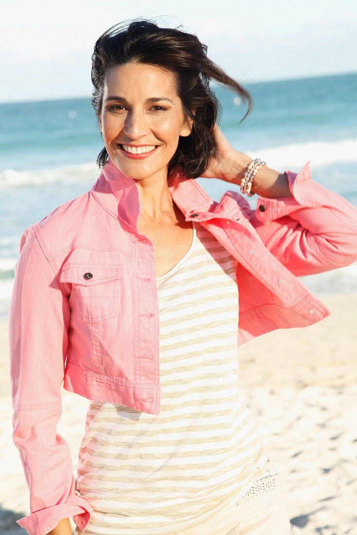 Brünette Frau mit rosa Jeans-Bolero am Strand