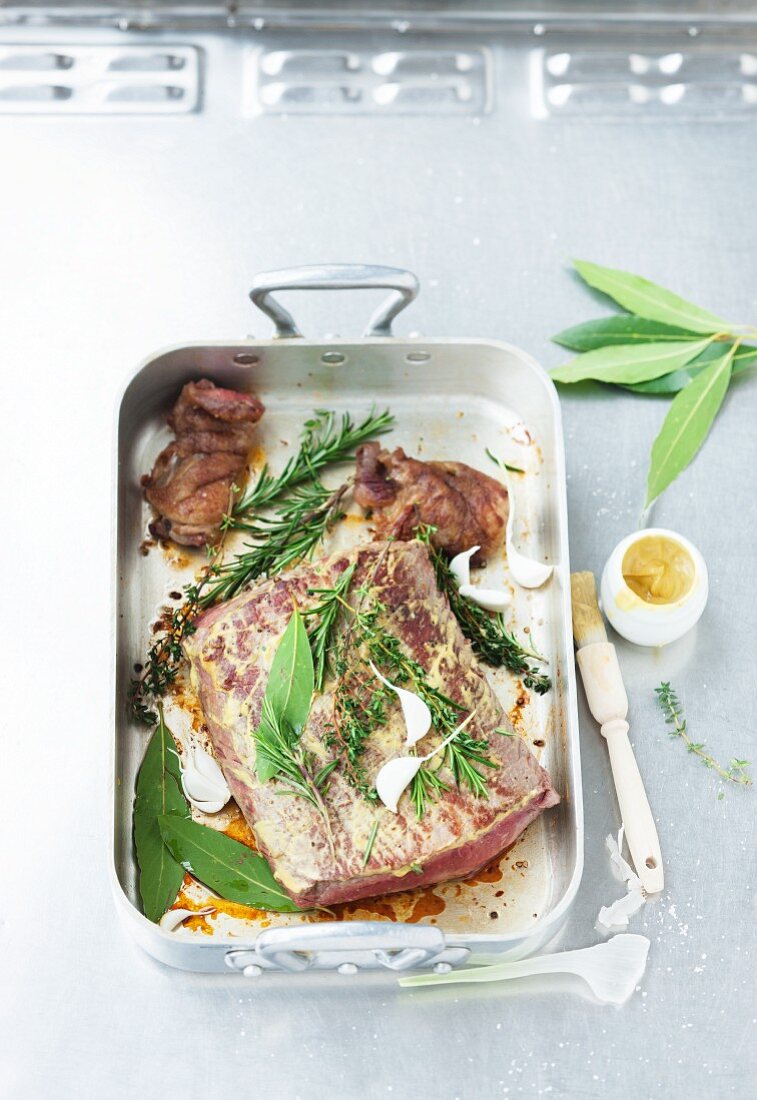 Roast beef with herbs and garlic in a roasting tin
