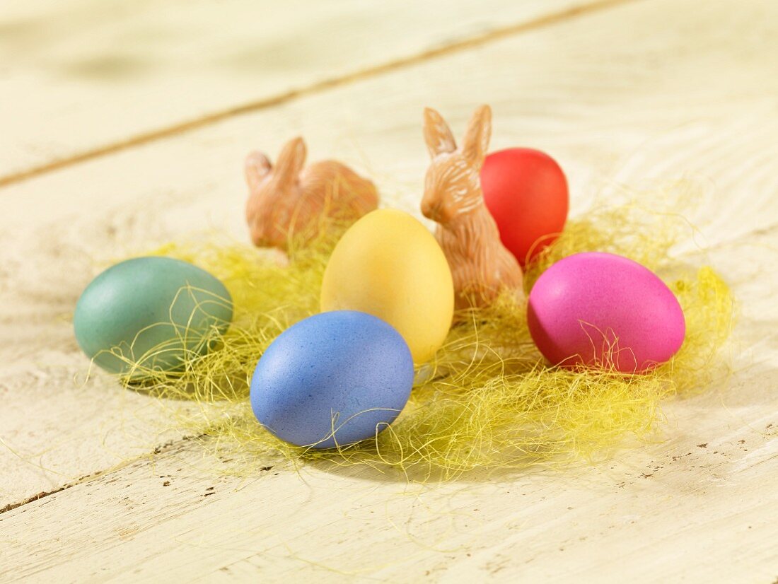 COlourful Easter eggs and terracotta Easter bunnies in decorative grass