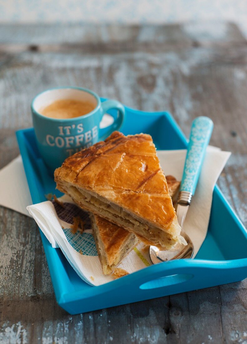 Two slices of galette des rois and coffee on a tray