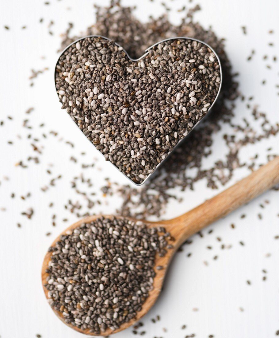 Chia seeds in a heart-shaped mould and on a wooden spoon