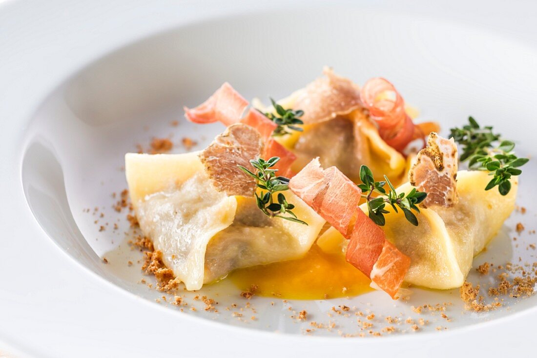 Meat-filled ravioli with pumpkin sauce, bacon and truffle