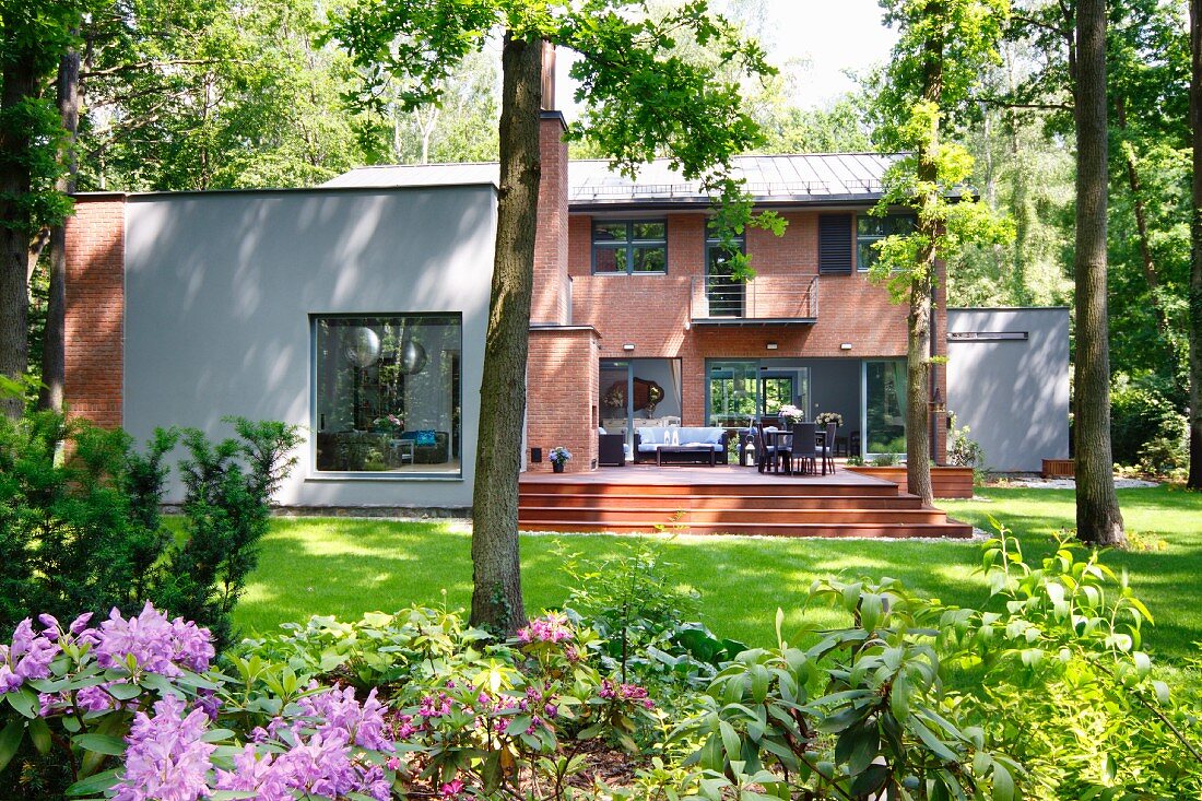 Modernes Wohnhaus mit Ziegelfassade und teilweise verputzten Flächen, Terrasse & sommerlichem Garten