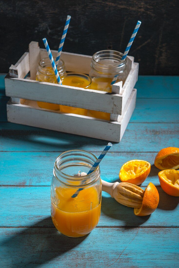 Orangensaft und ausgepresste Orangen