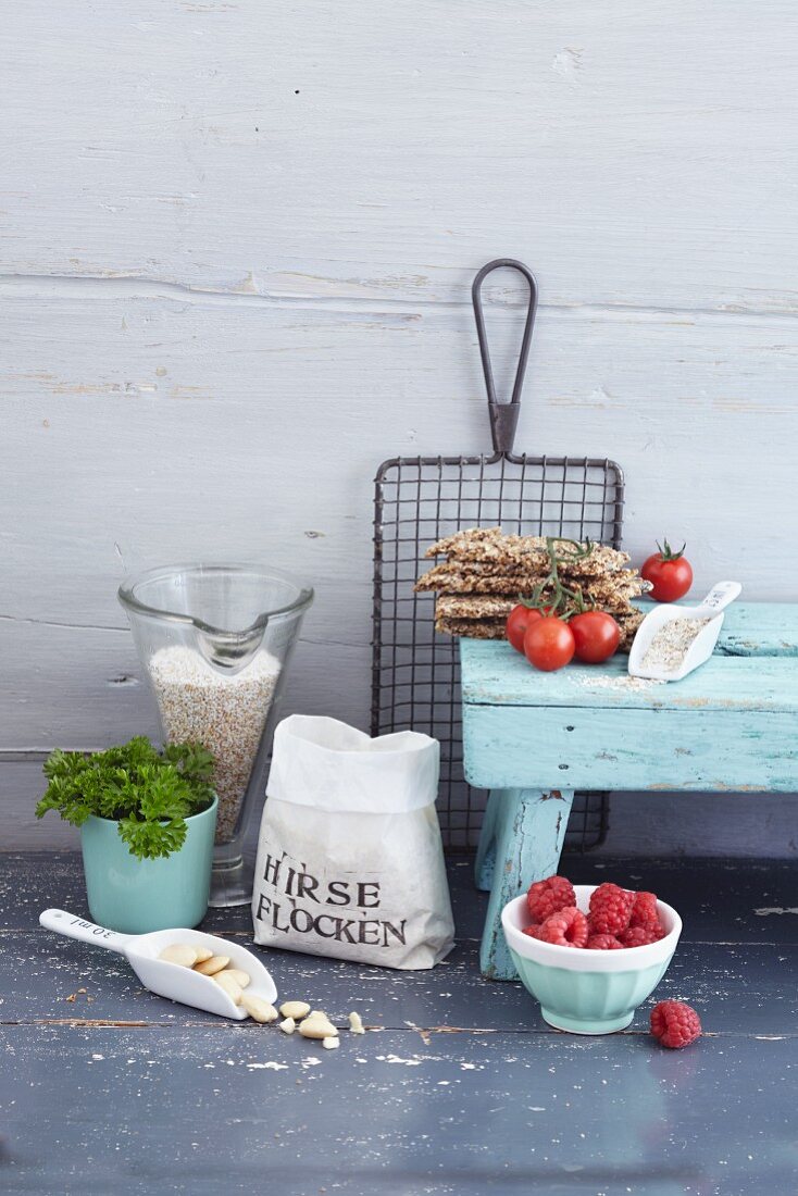 An arrangement of cereal flakes, raspberries, parsley, cherry tomatoes and crispbread