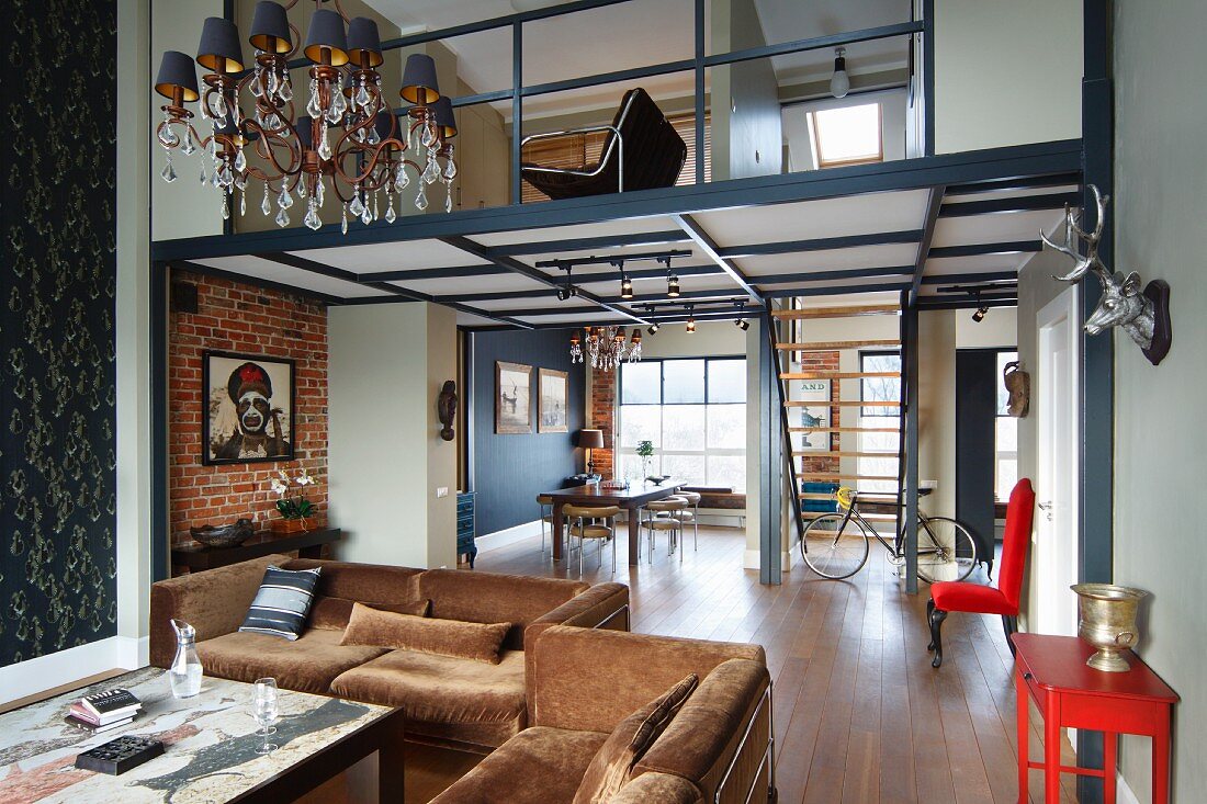 Lounge area with brown sofa set, dining area and staircase leading to mezzanine in open-plan interior