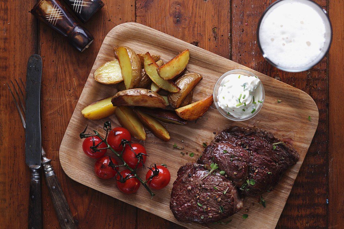 Beef steak with potatoes, cherry tomatoes and sour cream