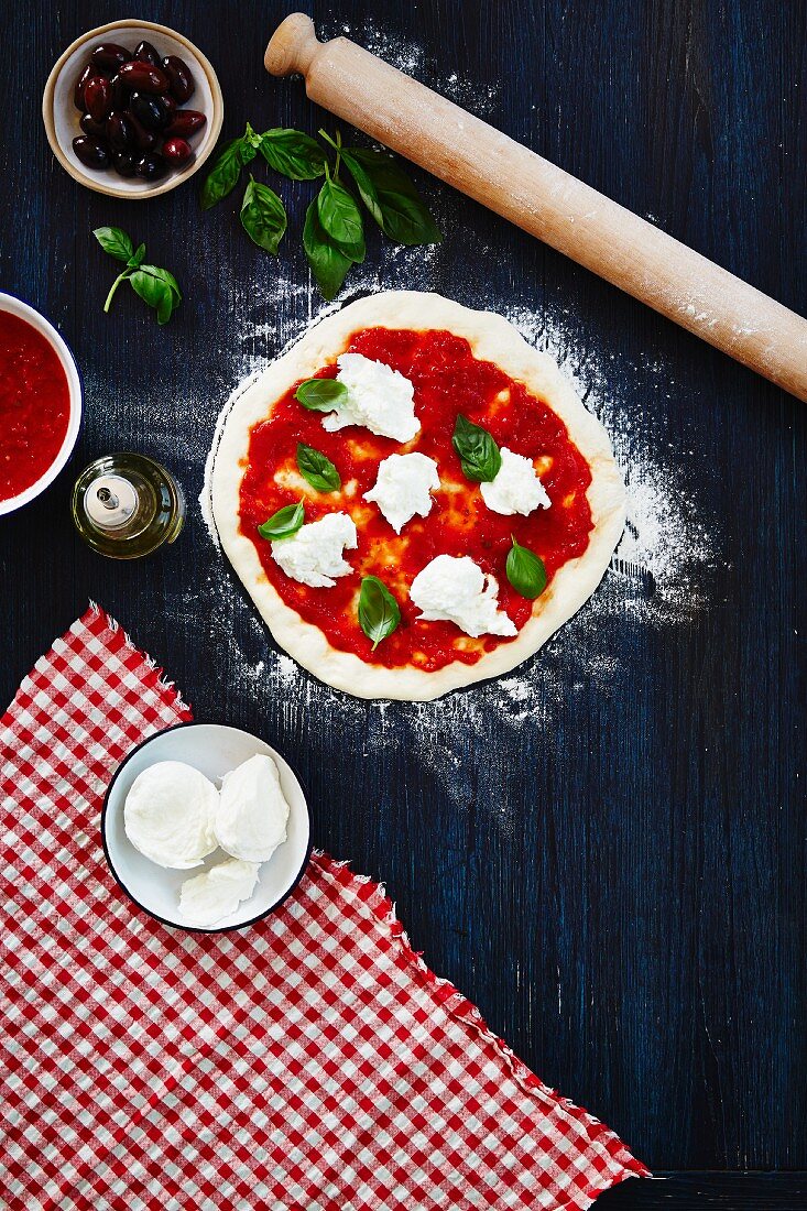 An unbaked pizza with tomatoes, mozzarella and basil