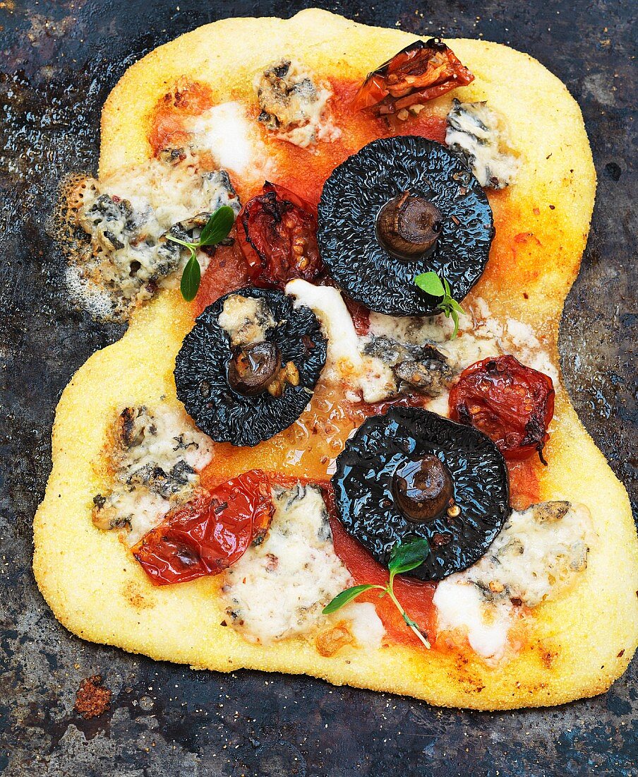 A pizza with mushrooms, blue cheese and tomatoes