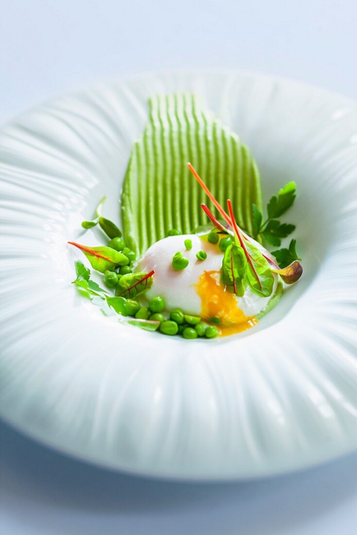 Poached eggs with young peas and beetroot leaves on mushy peas