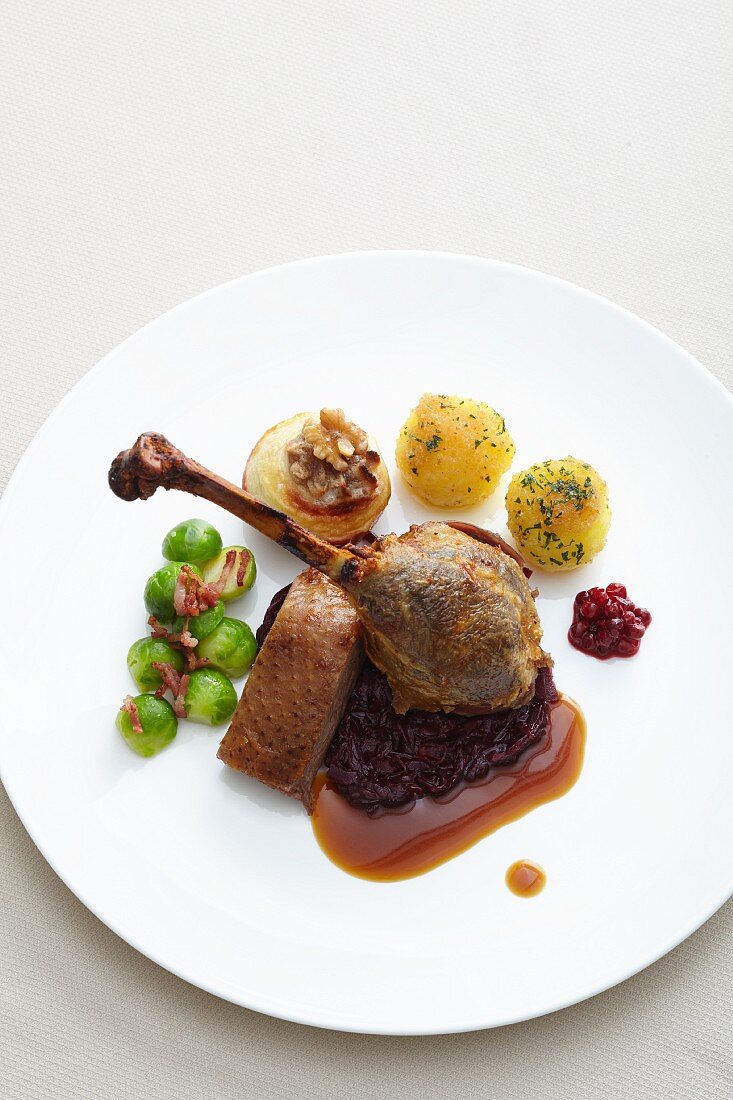 Goose leg with red cabbage, potato dumpling, baked apples and Brussels sprouts