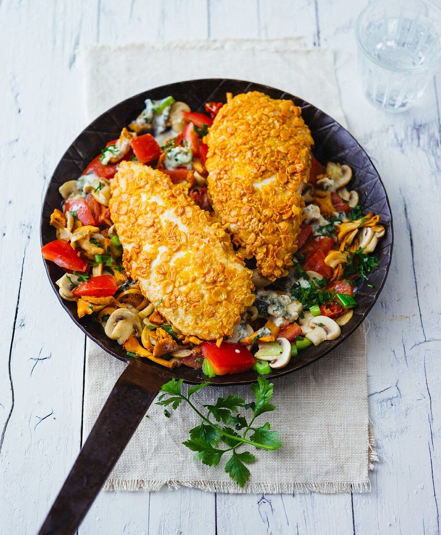 Chicken breast coated with soya flakes in a pan of fried mushrooms and vegetables