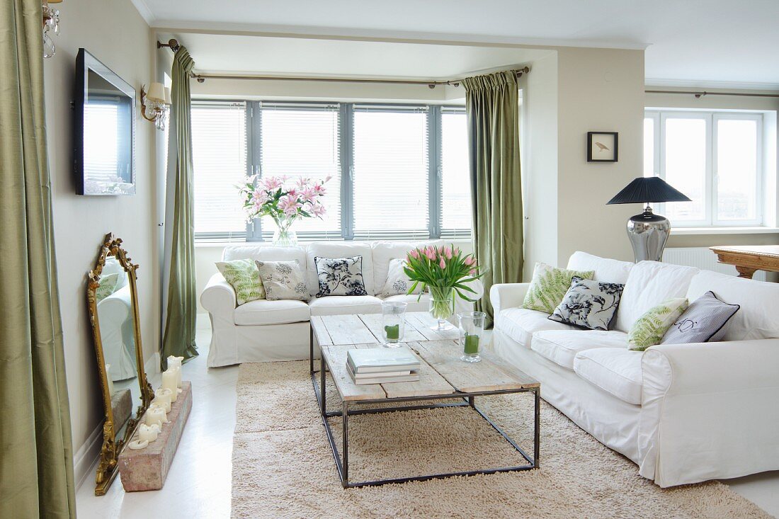 Coffee table with delicate metal frame and rustic wooden top on long-pile rug and white sofa set in corner of living room