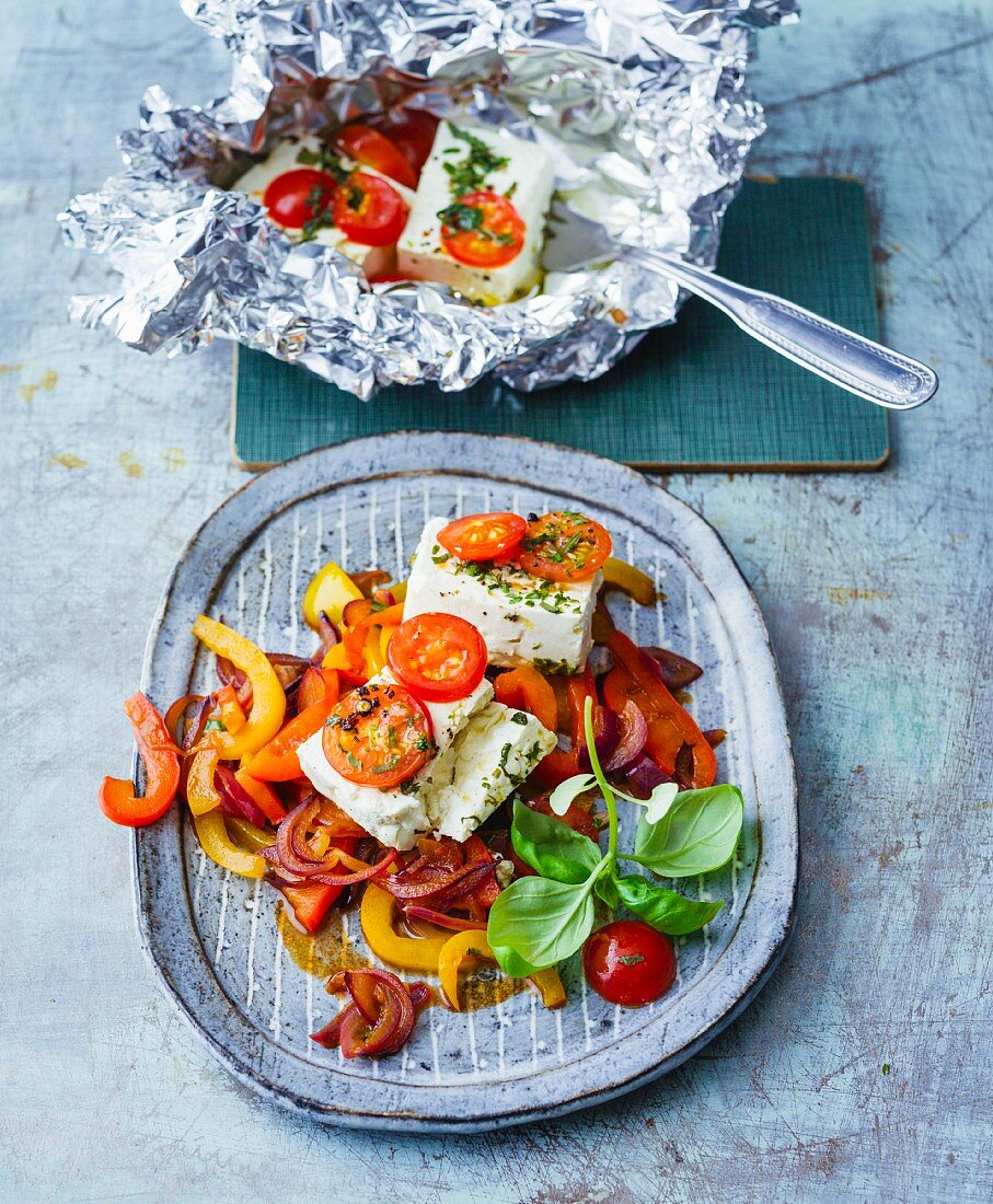 Feta cheese with cherry tomatoes in aluminium foil with balsamic vegetables