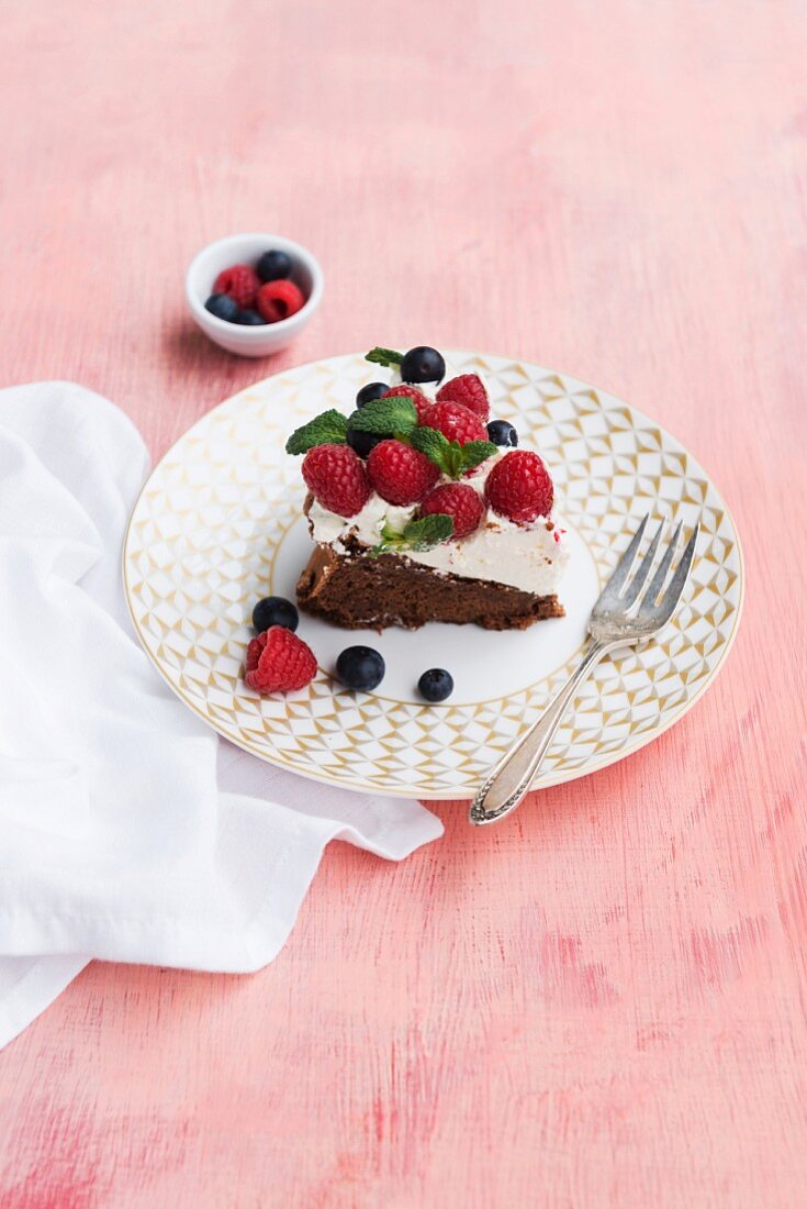 A slice of chocolate cake with cream and fresh berries