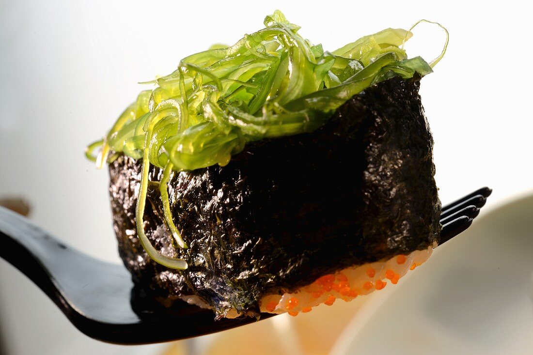A maki sushi with glass noodles on a fork (close-up)