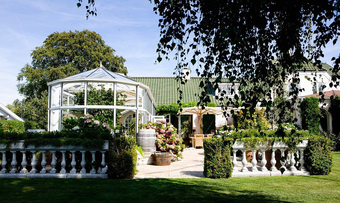 Steinbalustrade um sonnenbeschienene Terrasse mit Wintergarten