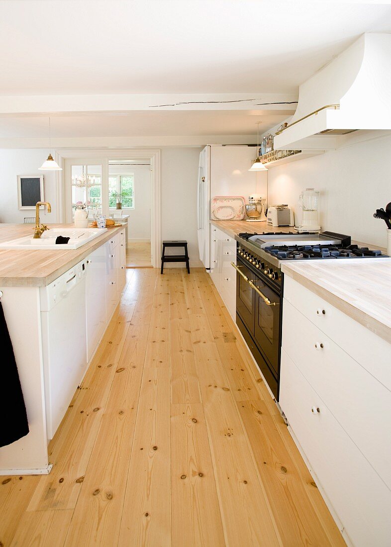 Kitchen counter with white base units and free-standing counter in kitchen with wooden floor