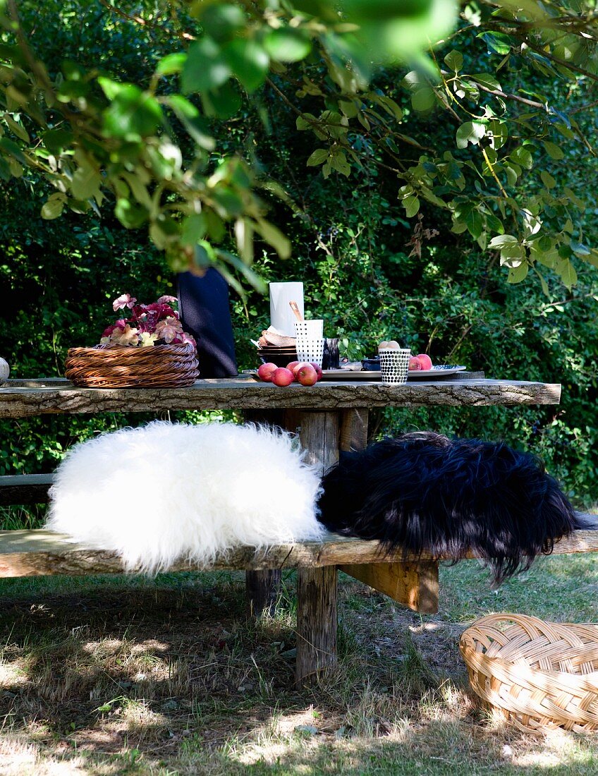 Black and white fur cushions on rustic bench at table set for breakfast