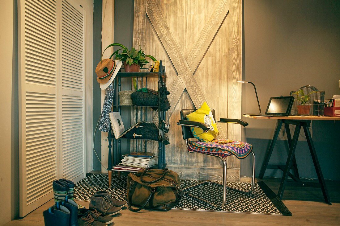 Wohnraum mit Schreibtisch & offenem Wandregal sowie Rucksack und Schuhe vor Schrank mit Lamellentüren