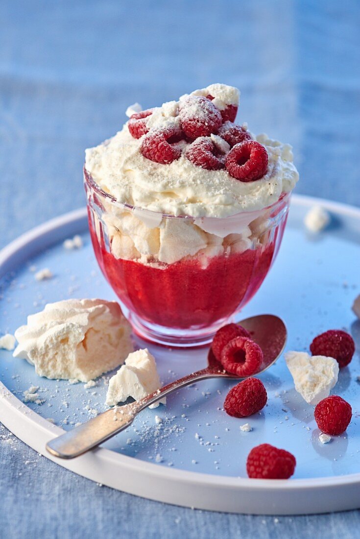 An ice cream sundae with raspberry sauce, meringue, cream and fresh raspberries