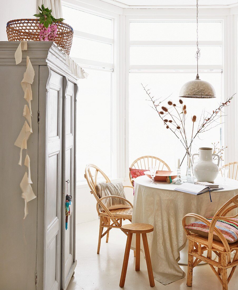 Dining room with wicker chairs, Oriental, silver pendant lamp and country-house cupboard in foreground