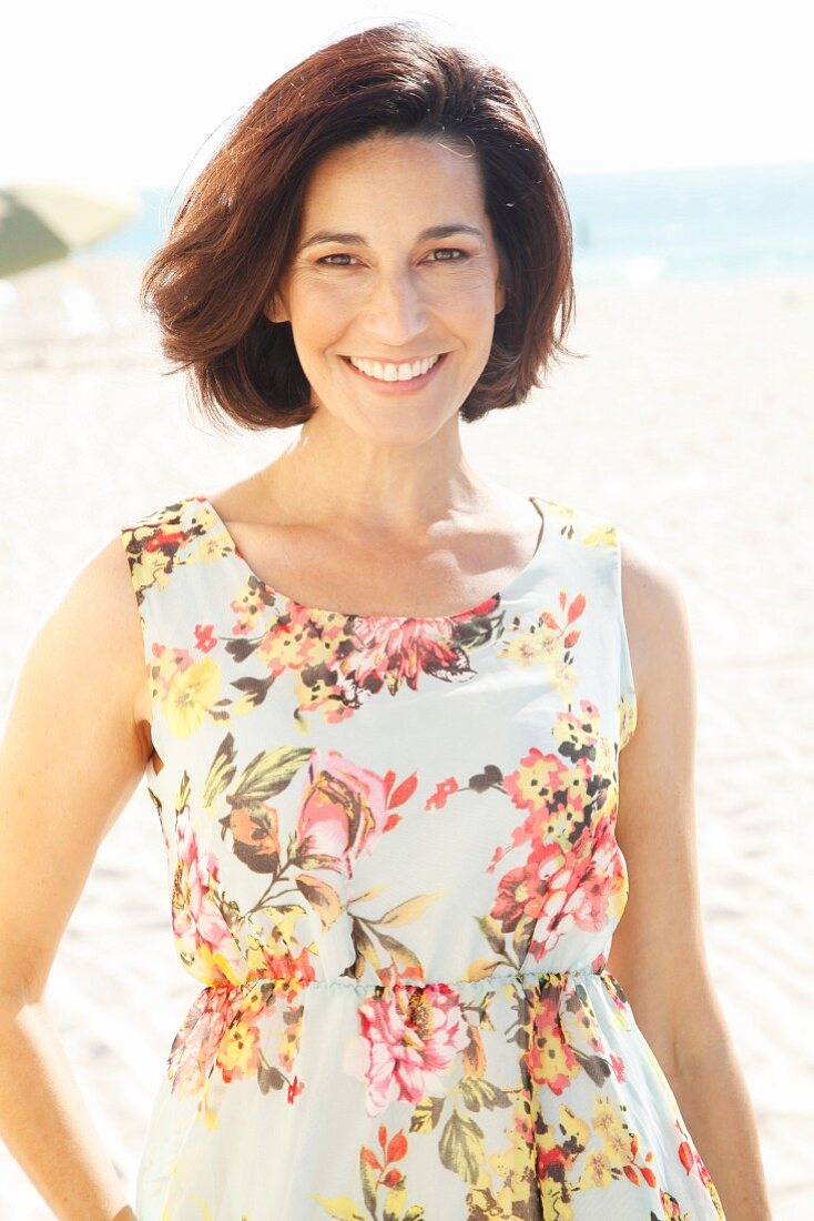 Brunette woman wearing floral summer dress on beach