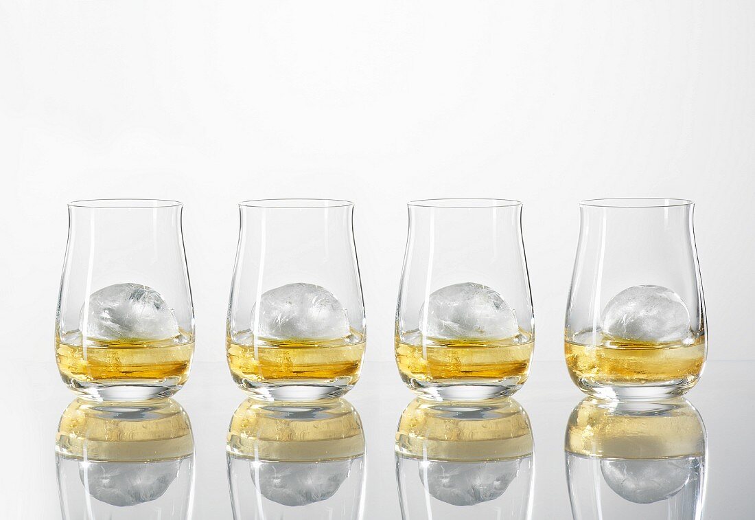 Four glasses of whiskey with ice cubes