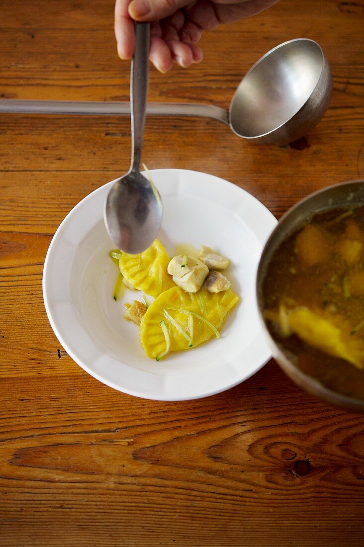 Fish soup with sage ravioli being served