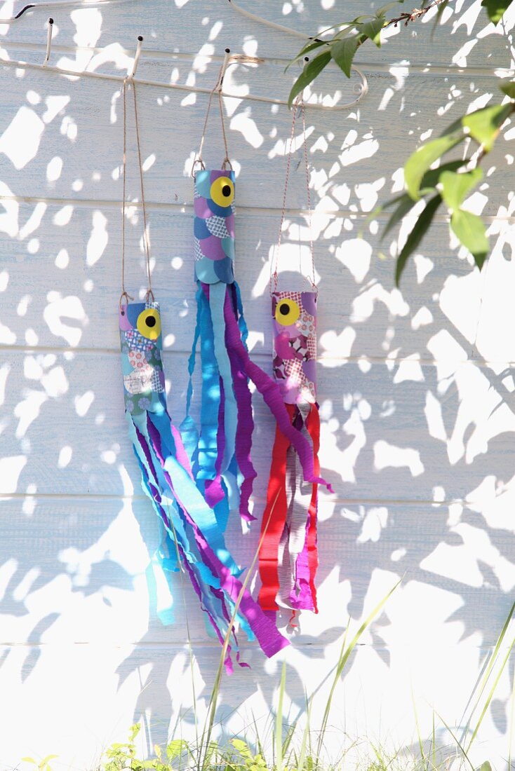 Hand-crafted, colourful crepe paper streamers hanging on white wooden facade