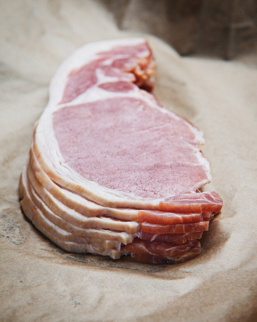 A stack of raw bacon on parchment paper