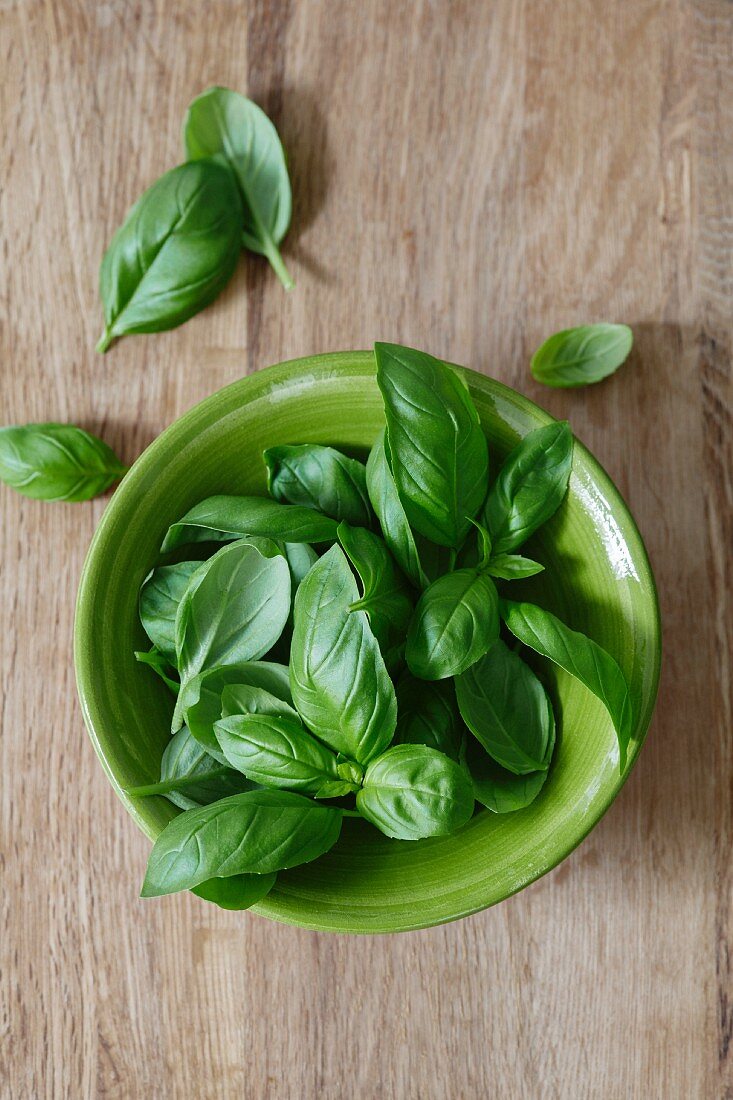 Fresh basil leaves in a ceramic bowl (seen from above)
