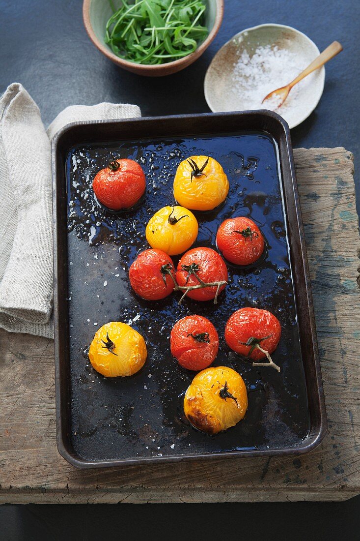 Oven-roasted red and yellow tomatoes on a baking tray