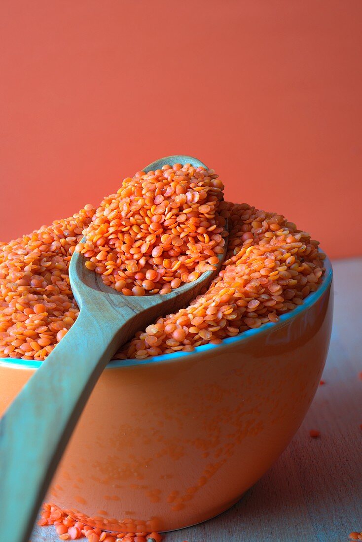 Red lentils in a bowl with a wooden spoon