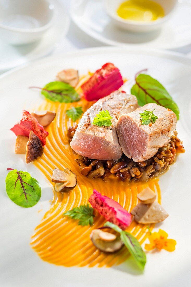 Veal fillet on a bed of risotto with sunflower seeds, pumpkin seeds and hazelnuts on a pumpkin purée