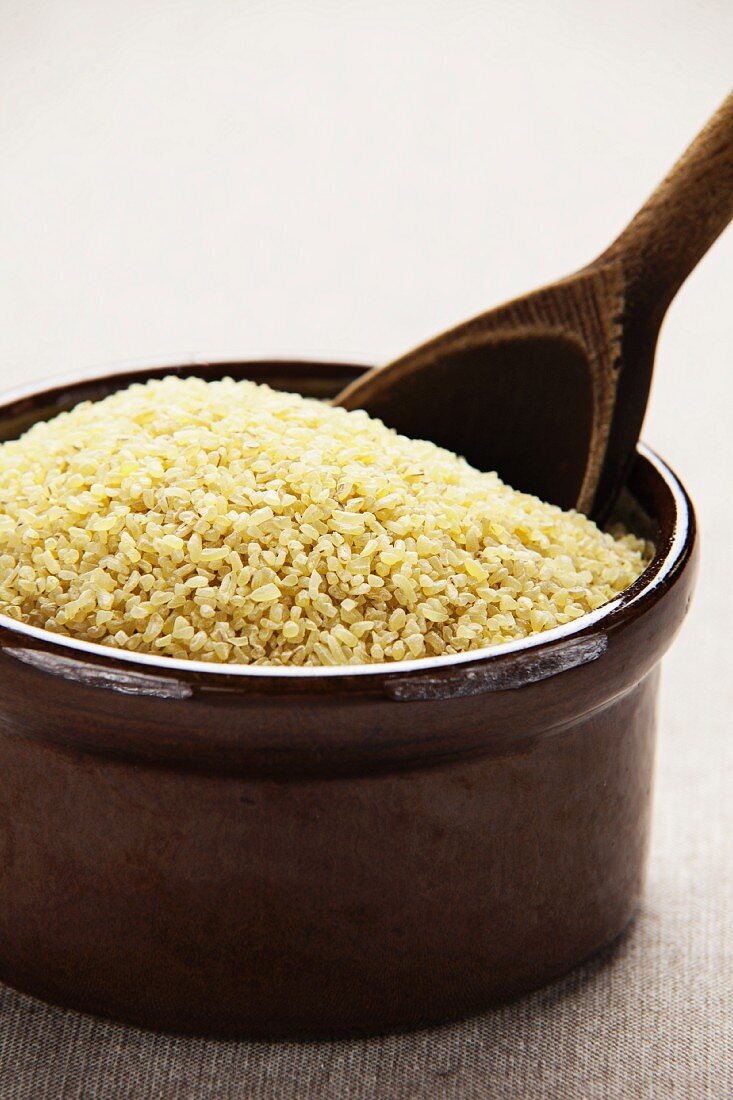 Bulgur wheat in a ceramic bowl with a wooden spoon